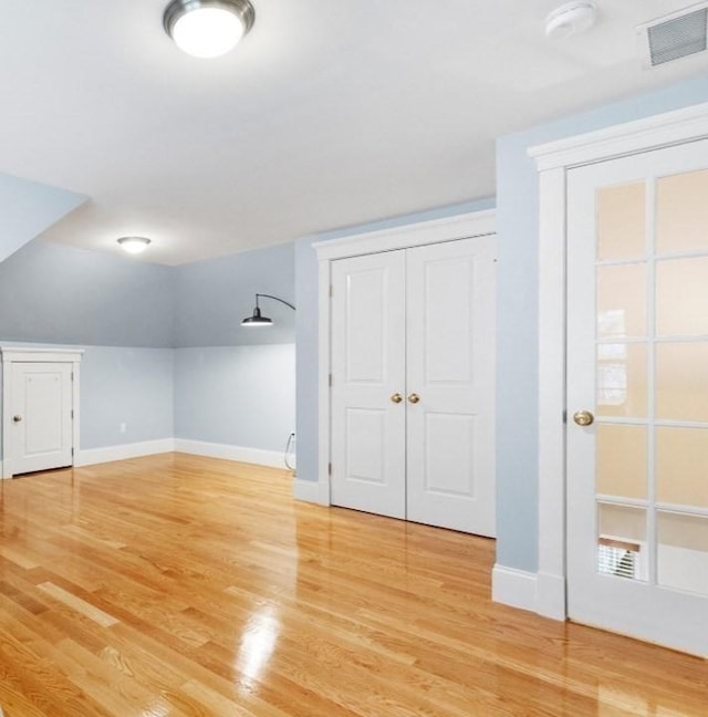 additional living space with light wood-style flooring, baseboards, and visible vents