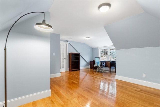 additional living space featuring light wood-style flooring, baseboards, and vaulted ceiling