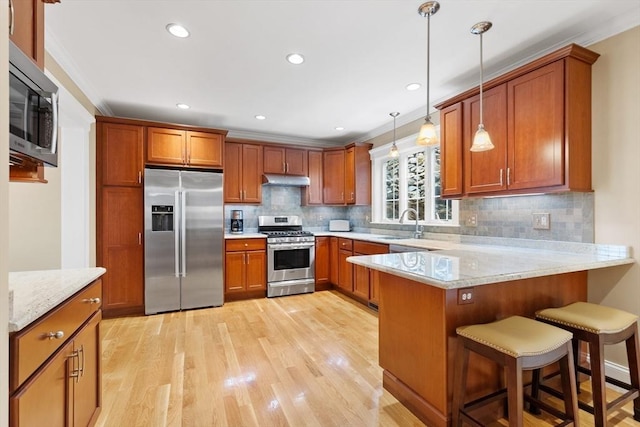 kitchen featuring a peninsula, brown cabinetry, appliances with stainless steel finishes, and ornamental molding