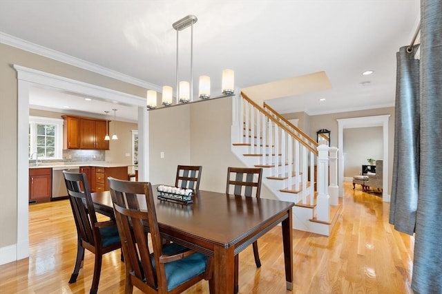 dining room with crown molding, stairway, recessed lighting, light wood-style flooring, and an inviting chandelier