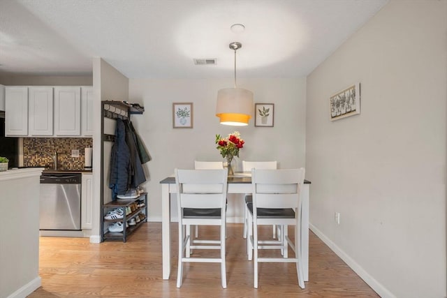 dining space featuring visible vents, light wood-style flooring, and baseboards