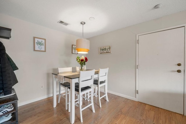 dining space featuring wood finished floors, visible vents, and baseboards