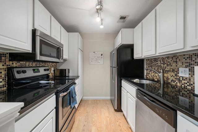 kitchen featuring visible vents, appliances with stainless steel finishes, light wood-style floors, white cabinetry, and a sink