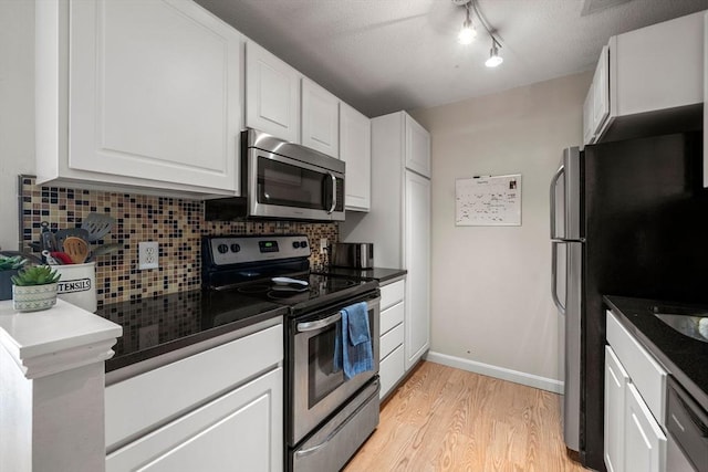 kitchen with decorative backsplash, appliances with stainless steel finishes, white cabinets, light wood-type flooring, and baseboards