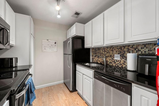 kitchen with dark countertops, visible vents, stainless steel appliances, and a sink