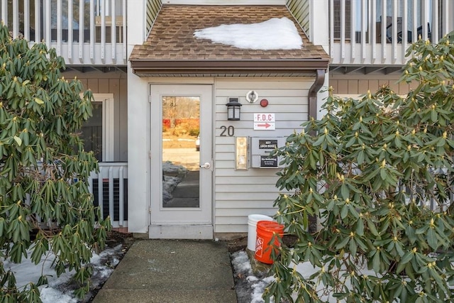 doorway to property featuring a shingled roof and a balcony