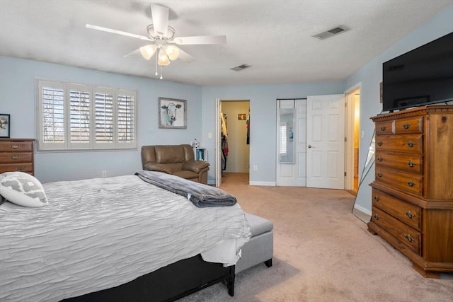 bedroom with light carpet, ceiling fan, visible vents, and baseboards