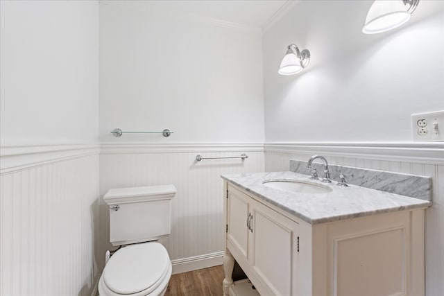 bathroom featuring wood-type flooring, crown molding, vanity, and toilet