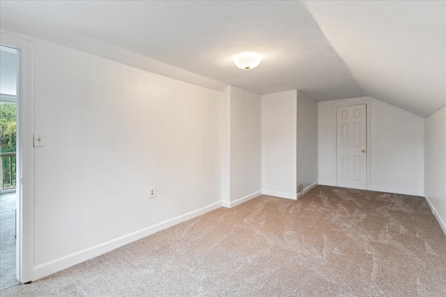 additional living space featuring light colored carpet and vaulted ceiling