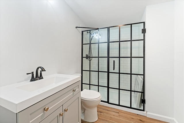 bathroom featuring hardwood / wood-style flooring, a tile shower, vanity, and toilet