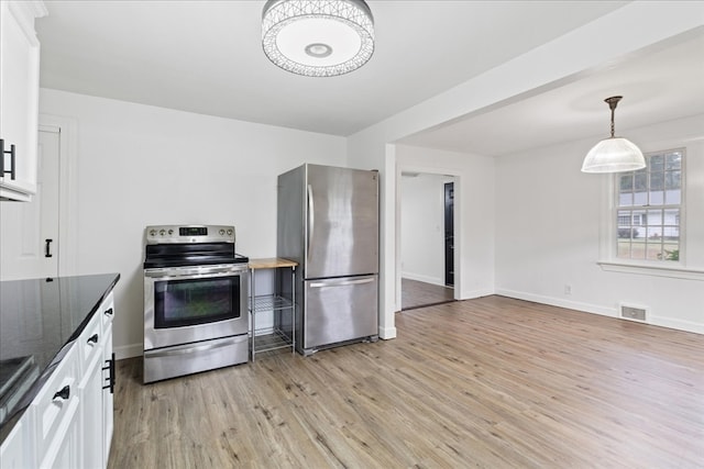 kitchen with white cabinets, decorative light fixtures, stainless steel appliances, dark stone countertops, and light hardwood / wood-style floors