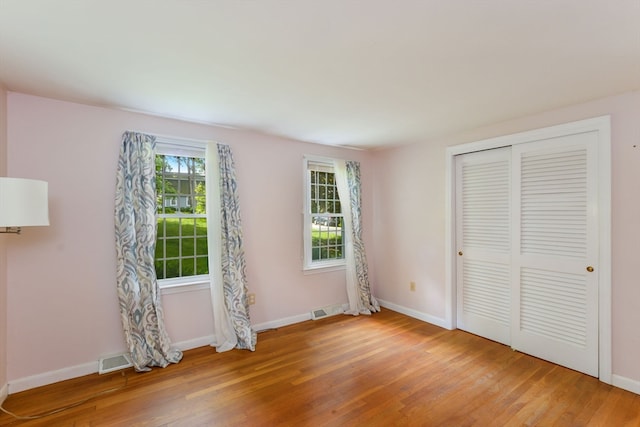 unfurnished bedroom featuring a closet, wood-type flooring, and multiple windows