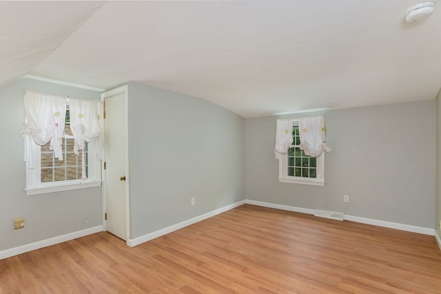 empty room featuring light wood-type flooring and vaulted ceiling