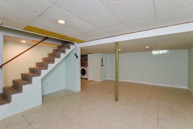 basement featuring washer / dryer, light tile patterned flooring, and a drop ceiling