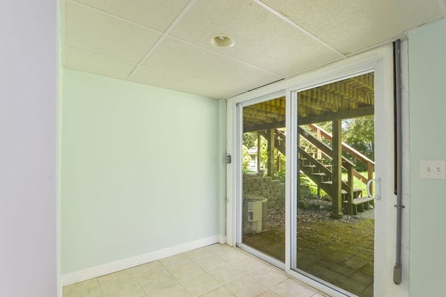 doorway to outside featuring light tile patterned floors and a drop ceiling