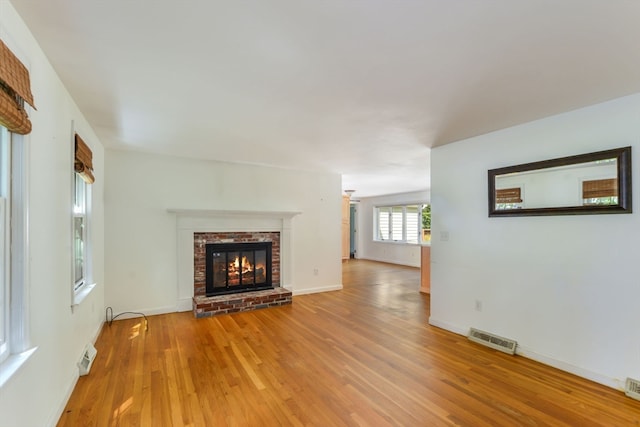 unfurnished living room featuring a brick fireplace and light hardwood / wood-style flooring