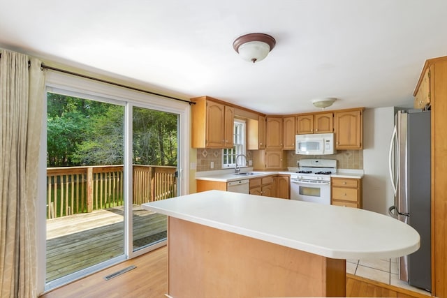 kitchen featuring white appliances, backsplash, sink, and light hardwood / wood-style flooring