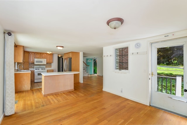 kitchen featuring light wood-type flooring, sink, white appliances, and tasteful backsplash