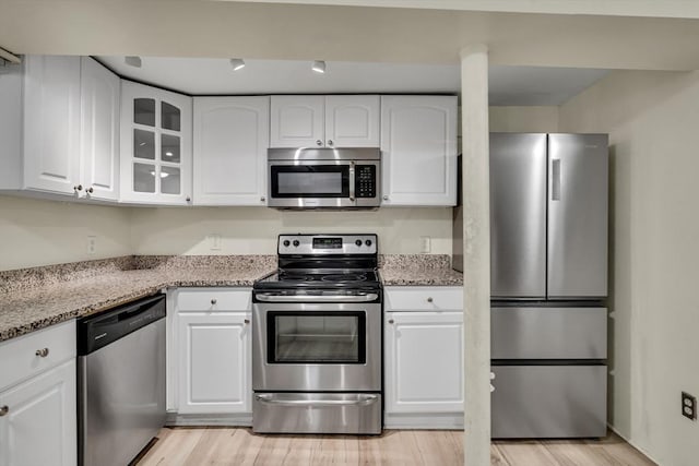 kitchen with white cabinetry, light stone counters, and appliances with stainless steel finishes