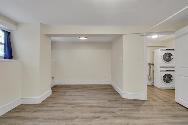 laundry area with light wood-type flooring and stacked washer / dryer