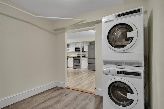 clothes washing area featuring light hardwood / wood-style floors and stacked washer and clothes dryer