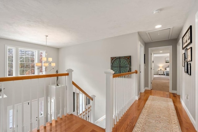 hallway with an inviting chandelier and light hardwood / wood-style flooring