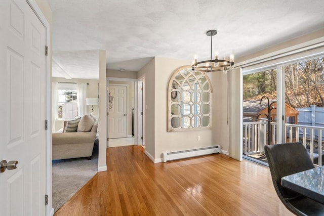 dining space featuring baseboard heating, an inviting chandelier, wood finished floors, and baseboards