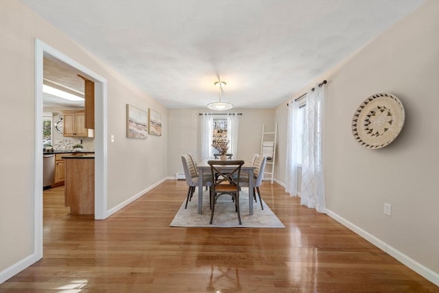 dining space with light wood-type flooring and baseboards