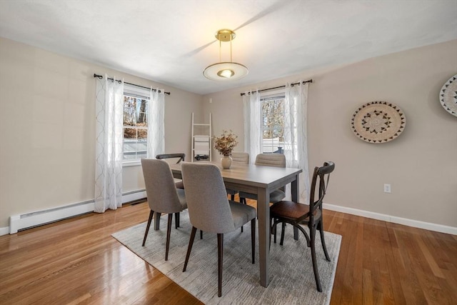 dining space featuring light wood finished floors, baseboards, and a baseboard heating unit