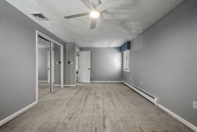 unfurnished bedroom with visible vents, a baseboard heating unit, baseboards, and carpet flooring