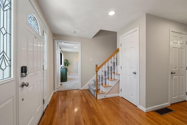 entrance foyer featuring stairway, light wood-style flooring, visible vents, and baseboards