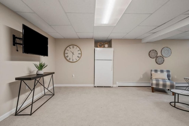 sitting room with a baseboard heating unit, baseboards, light colored carpet, and a drop ceiling