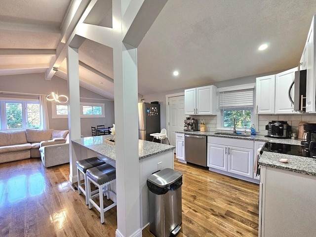 20 Upland Rd, Marlborough, MA 01752 - kitchen with appliances with stainless steel finishes, a kitchen bar, light stone countertops, a chandelier, and light wood-style floors