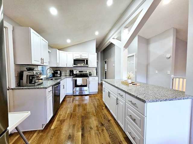 20 Upland Rd, Marlborough, MA 01752 - kitchen with stainless steel appliances, lofted ceiling, light stone counters, a center island, and dark wood-style flooring