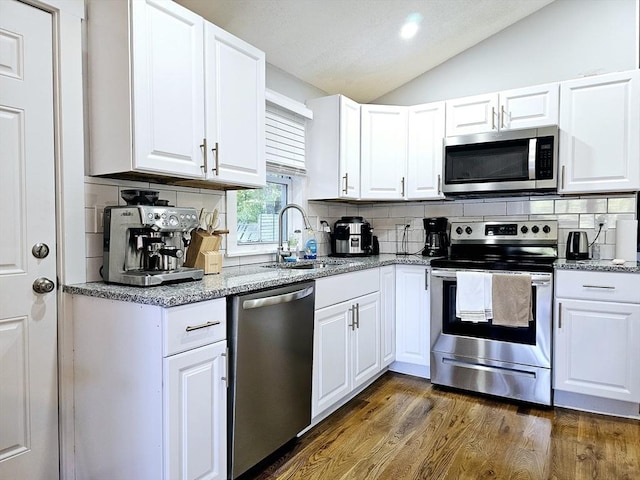 20 Upland Rd, Marlborough, MA 01752 - kitchen featuring appliances with stainless steel finishes, lofted ceiling, backsplash, dark wood finished floors, and white cabinetry
