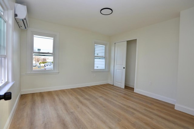 unfurnished bedroom featuring light hardwood / wood-style floors and a wall unit AC