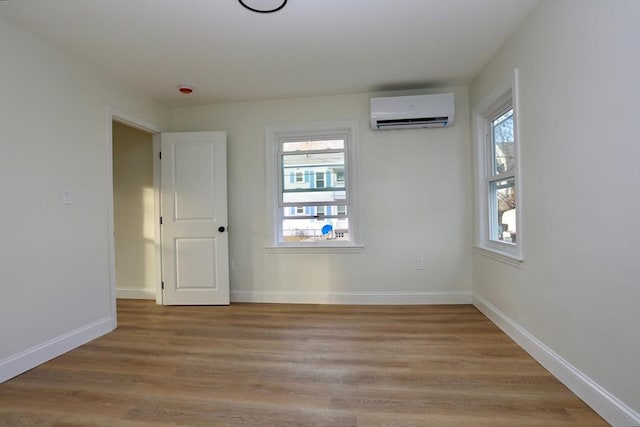 empty room with light wood-type flooring and an AC wall unit