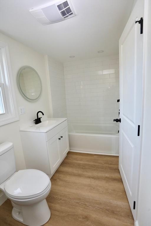 full bathroom featuring tiled shower / bath, vanity, wood-type flooring, and toilet