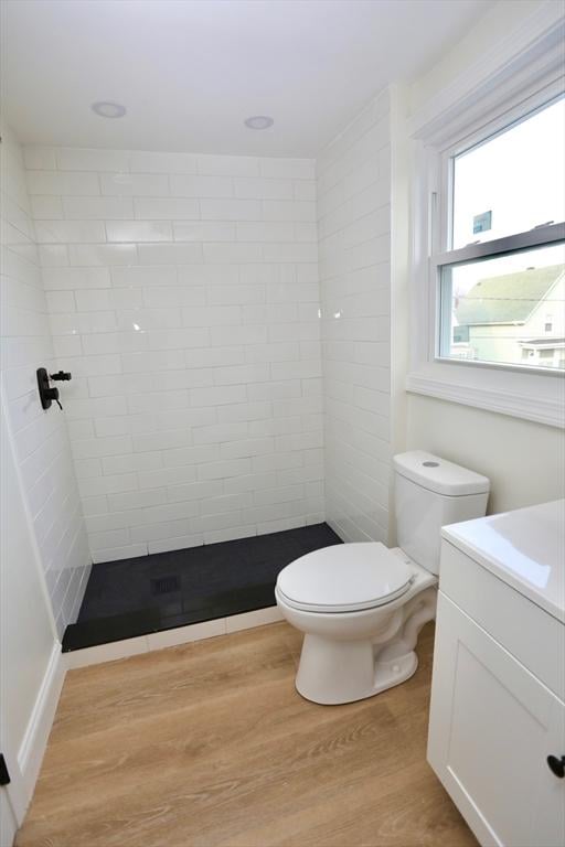 bathroom featuring tiled shower, wood-type flooring, vanity, and toilet