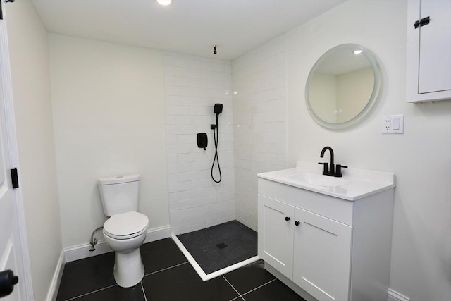 bathroom with tile patterned floors, vanity, a tile shower, and toilet