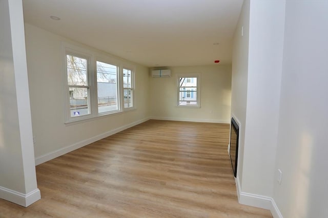 unfurnished room with a wall mounted air conditioner and light wood-type flooring