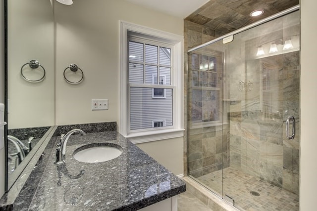 bathroom featuring a shower with door and vanity