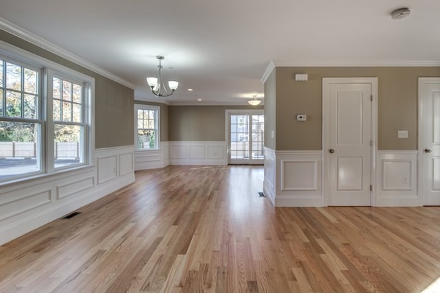 unfurnished room featuring ornamental molding, a notable chandelier, and light hardwood / wood-style flooring