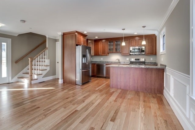 kitchen featuring a healthy amount of sunlight, ornamental molding, appliances with stainless steel finishes, and light hardwood / wood-style floors