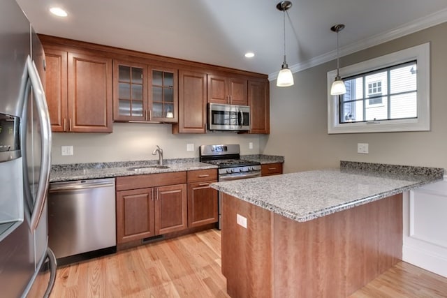 kitchen featuring stainless steel appliances, kitchen peninsula, sink, light stone countertops, and light hardwood / wood-style floors