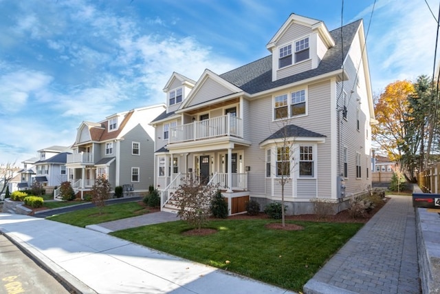 view of front of property featuring covered porch, a balcony, and a front yard