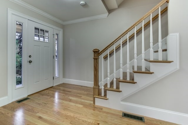 foyer entrance featuring light hardwood / wood-style floors and crown molding