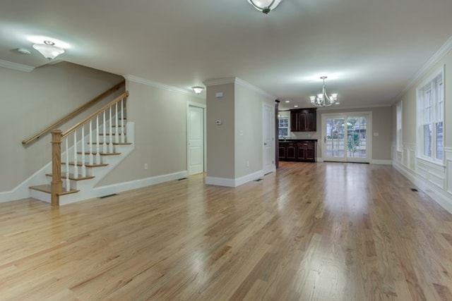 unfurnished living room featuring ornamental molding, an inviting chandelier, and light hardwood / wood-style flooring