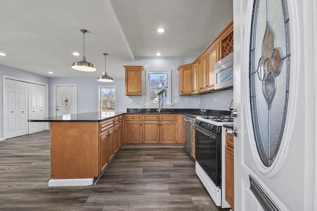 kitchen featuring recessed lighting, a peninsula, dark wood-style flooring, appliances with stainless steel finishes, and dark countertops