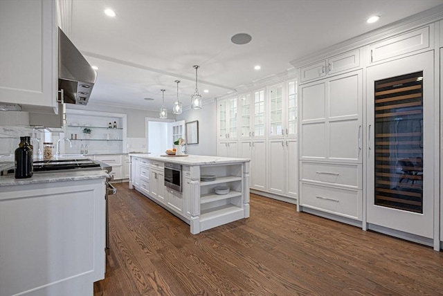 kitchen featuring white cabinetry, hanging light fixtures, range hood, and a kitchen island